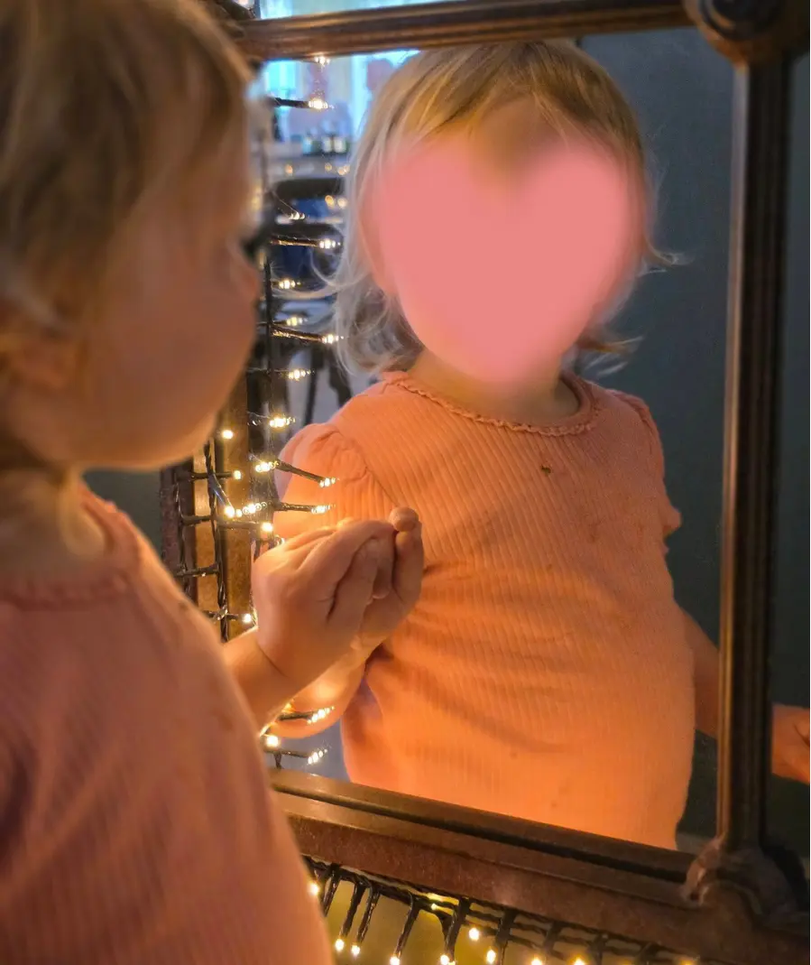 A young child looking into a mirror